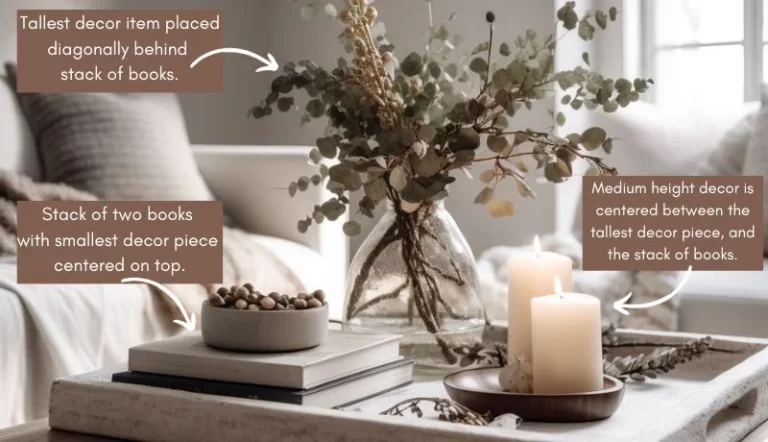 An infographic with text describing how to group Christmas coffee table decor in groups of three overlaid on top of an image of a coffee table with a tray, a stack of books, and holiday decor.