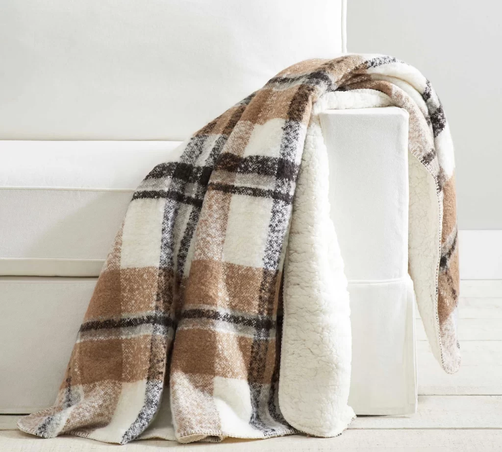 Lodge Plaid Sherpa Back Throw from Pottery Barn laid over a white sofa