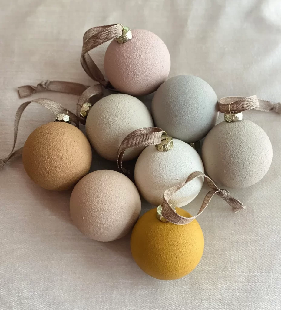 Matte textured Christmas ornaments on a white linen background