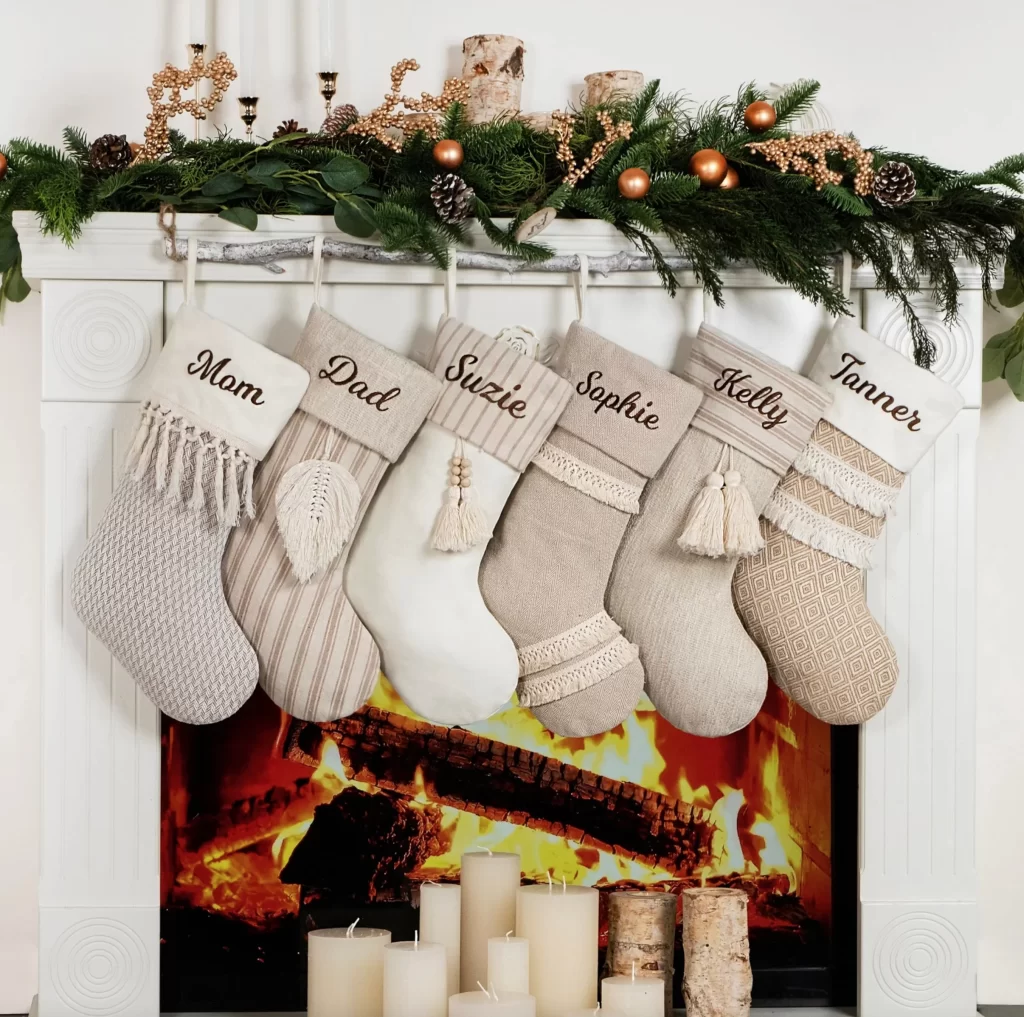 Personalized Boho Christmas Stockings on a fireplace with a mantle covered in Christmas garland